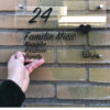 Doorzichtig plexiglas huisnummerbord met huisnummer en namen in zwart
